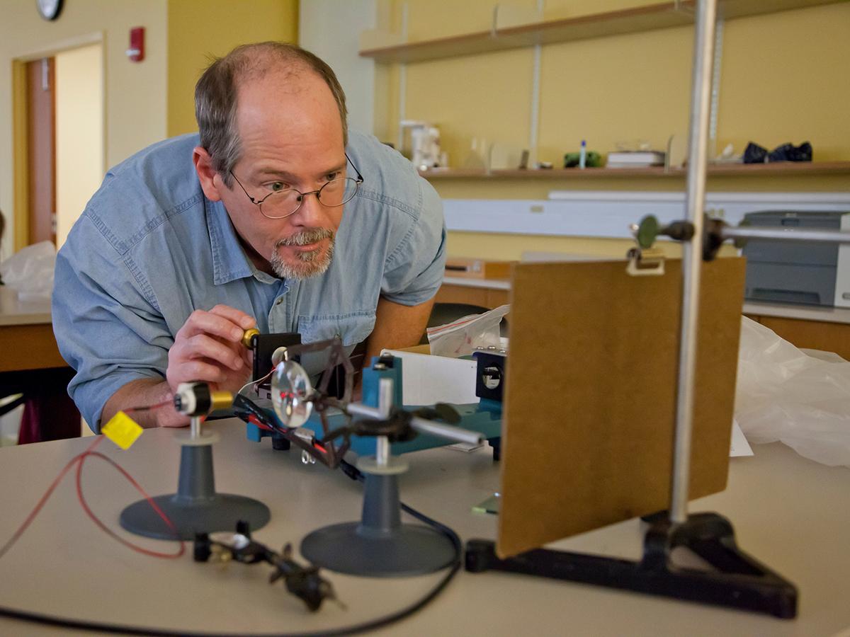 A physics professor sets up experiments for Physics 120 Lab in Ho Science Center