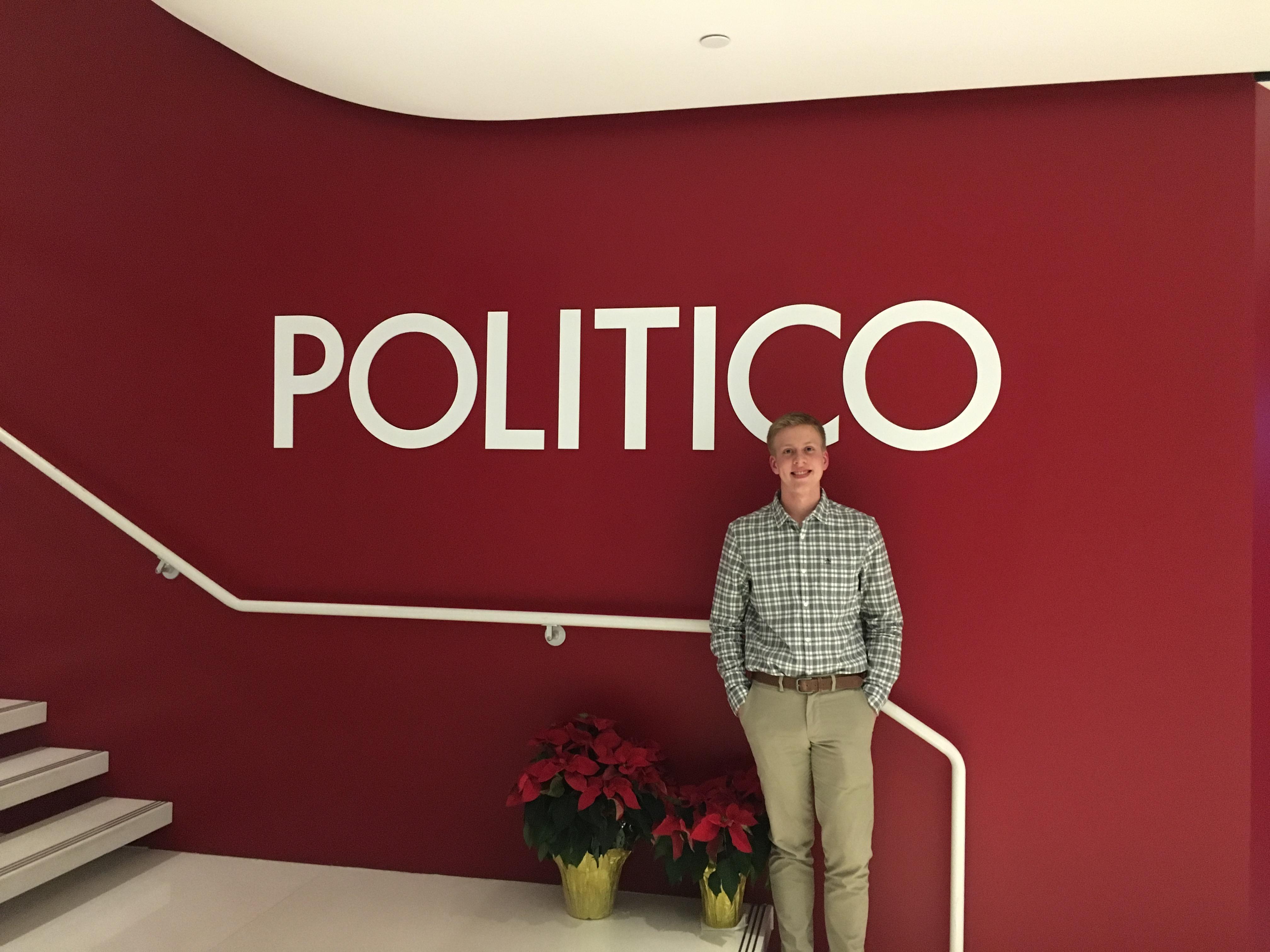 Student standing in front of the sign at Politico