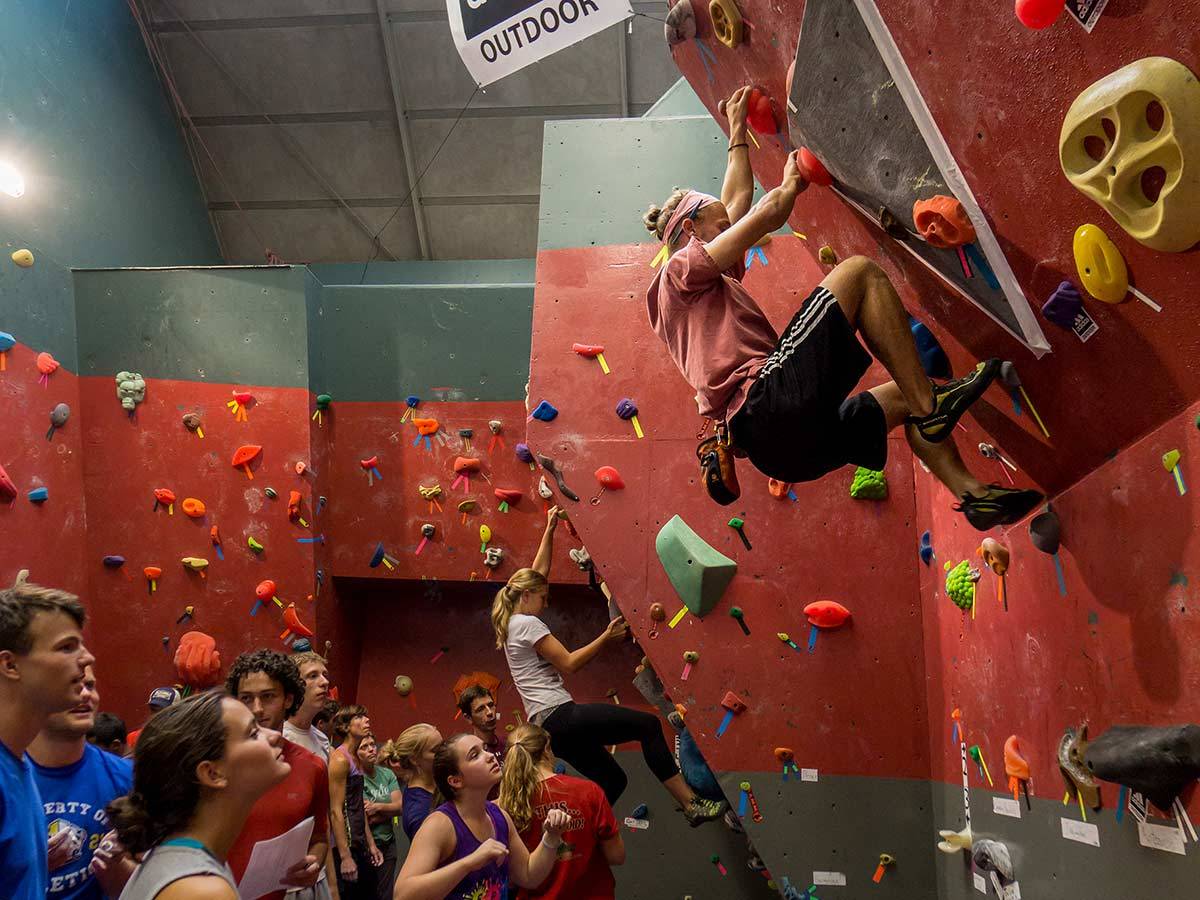 Students watch as another student scales a wall in the Angert Family Climbing Wall facility