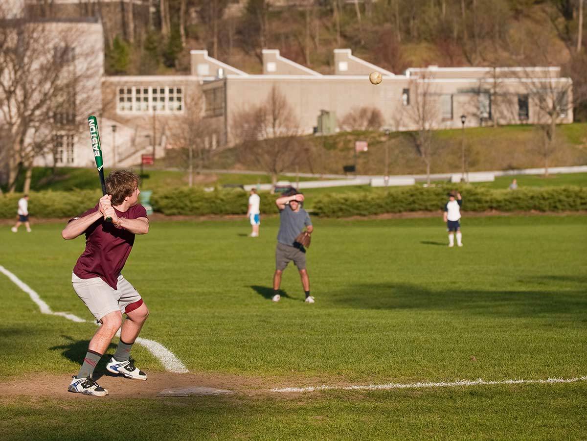 A student prepares to swing a bat at a pitched softball during an intramural game on Whitnall Field