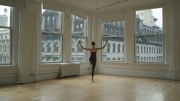 ballet dancer in empty studio looking onto city skyline