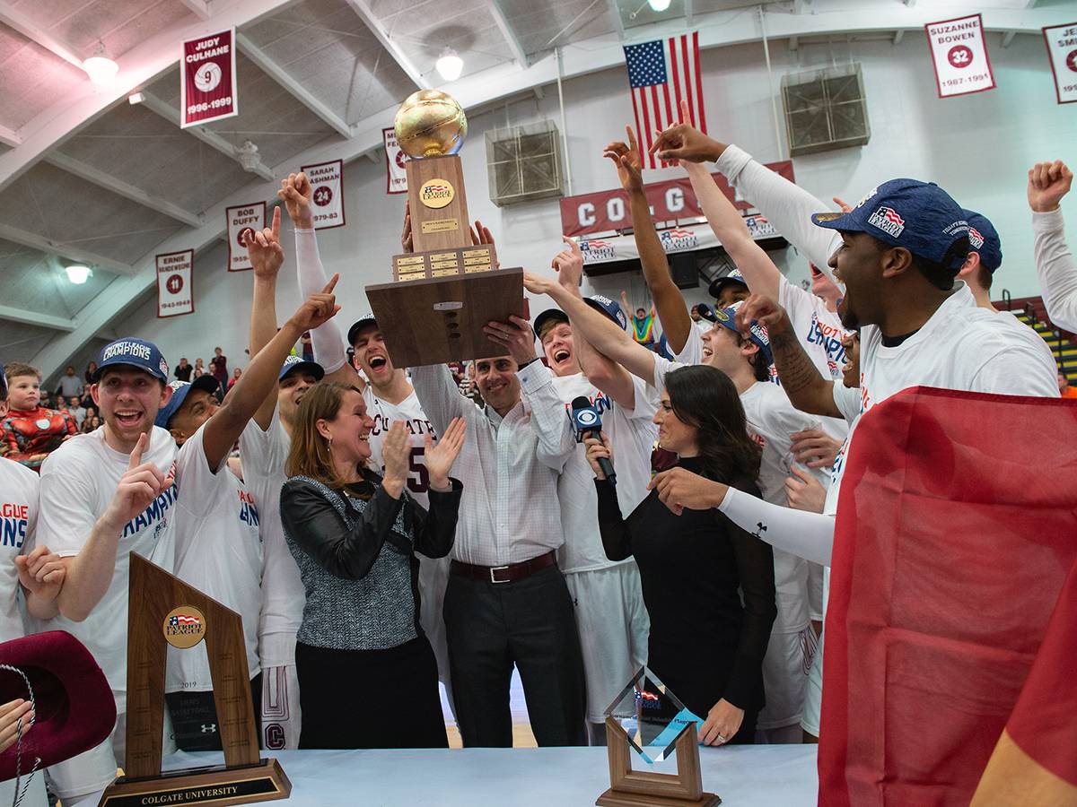Colgate Men's Basketball coach and team holding up the 2019 Patriot League Championship trophy.