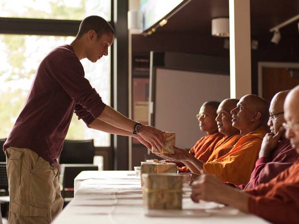 A student makes an offering to Buddhist monks.