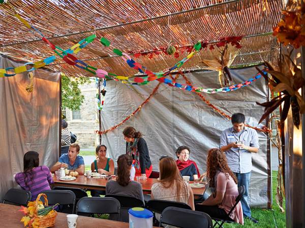 Students are celebrating Sukkot, the Jewish harvest festival, in a sukkah, which is a temporary structure that they built on the Quad.