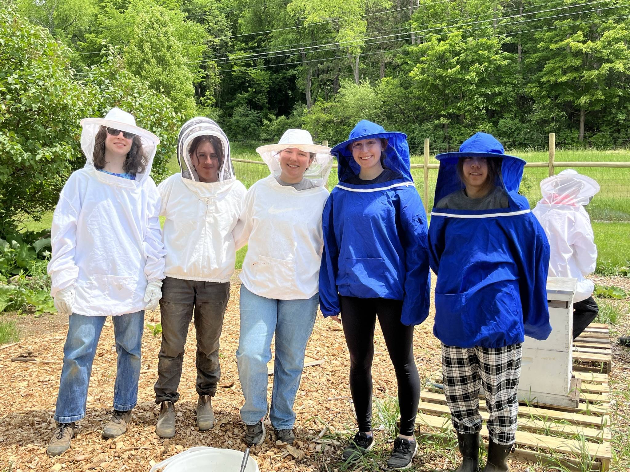 Five students wearing beekeeping suits and hoods while posing for a photo.
