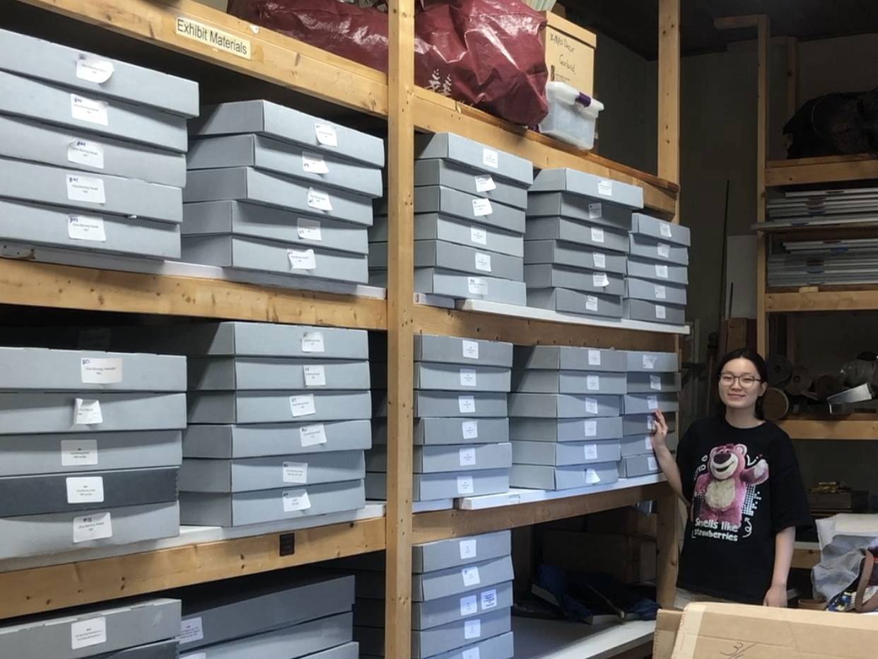 Cindy Chen stands along a wall of boxes of archived material