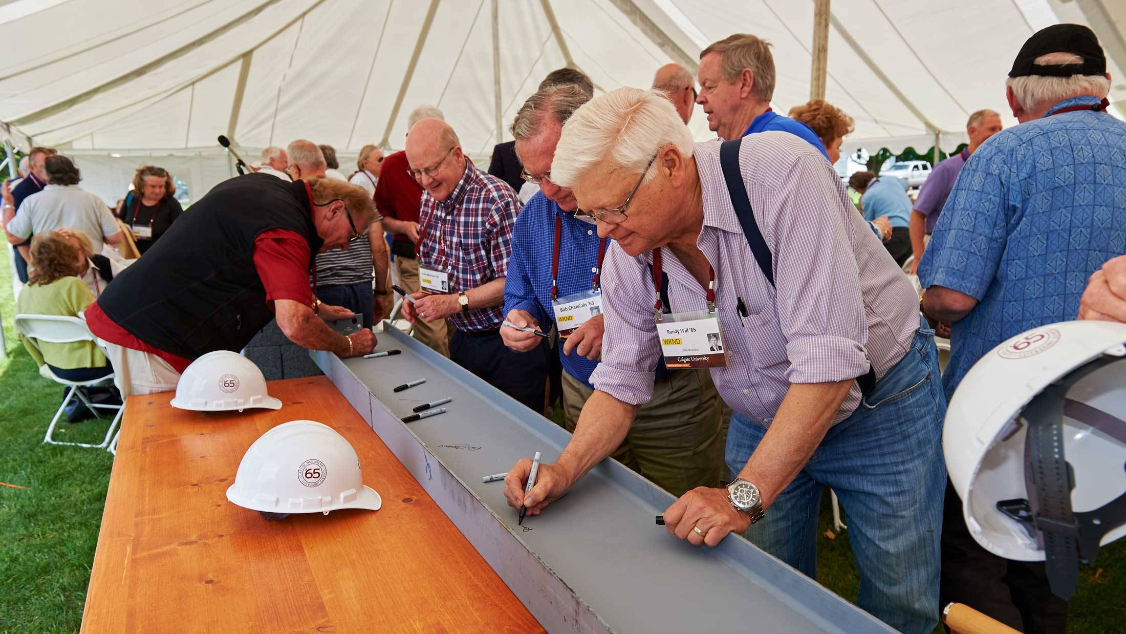 Members of the Class of 1965 sign a beam to be used in the construction of the Class of 1965 Arena