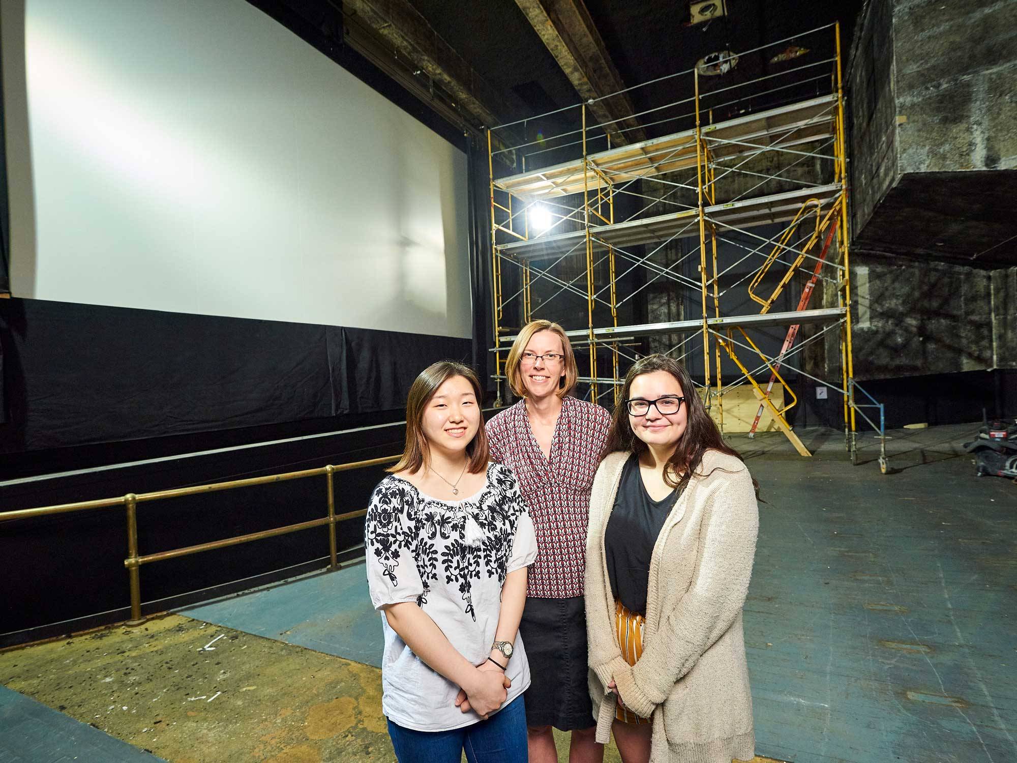 Chloe You ’22, Associate Professor Mary Simonson, and Molly Adelman ’21 stand in the Hamilton Theater during its renovation