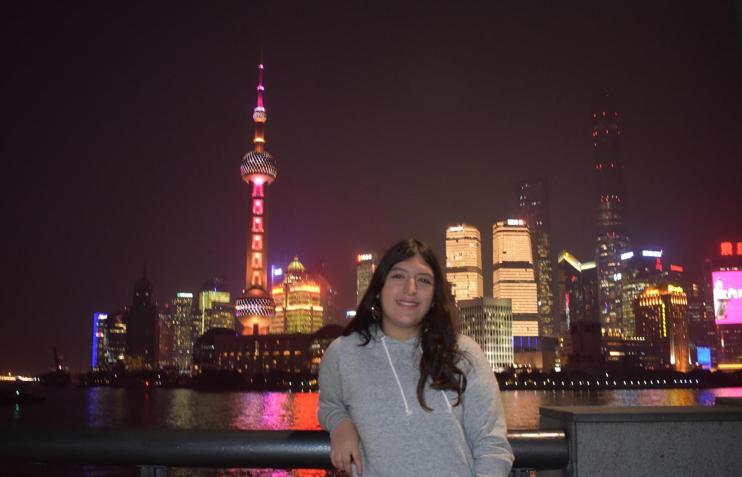 Elizabeth Gonzales with the nighttime Shanghai skyline in the background