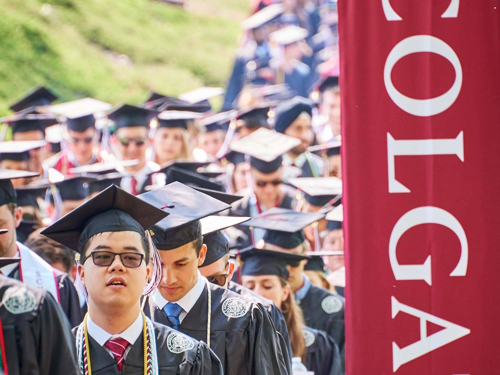 Students process into commencement 2019 past a Colgate Banner
