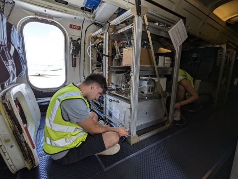 Photo of Joe Berberich '24 working on the research plane while wearing the yellow, high visibility vest.