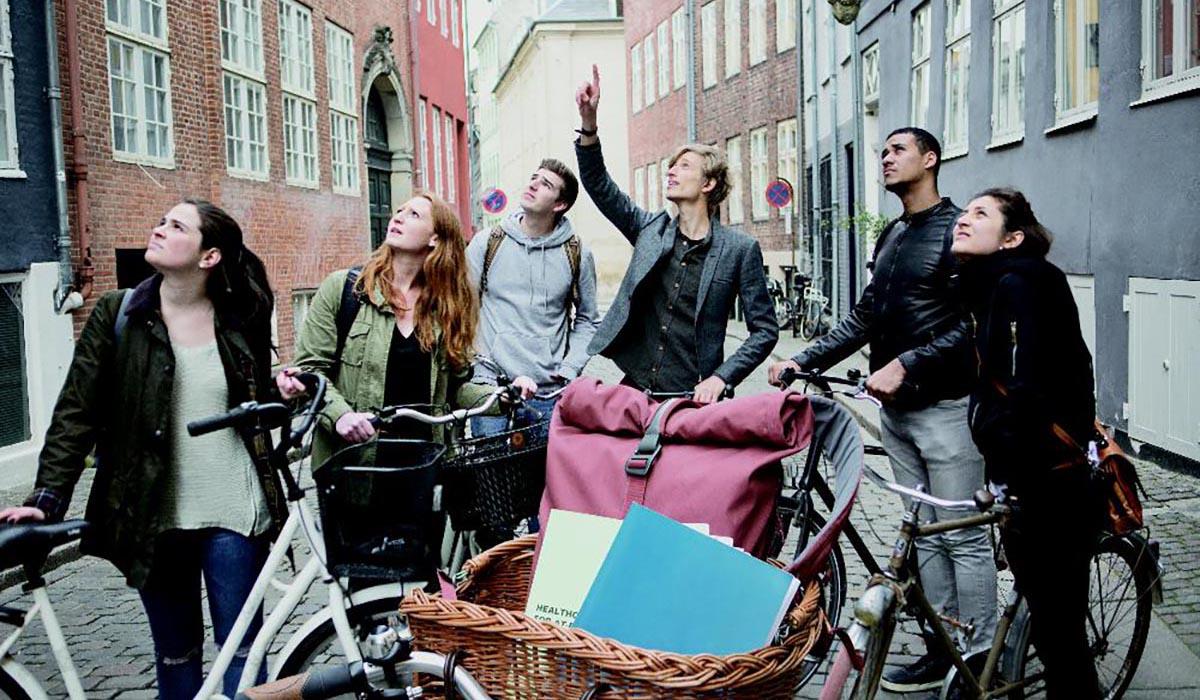 A professor points to an architectural feature as a class bikes in Copenhagen.