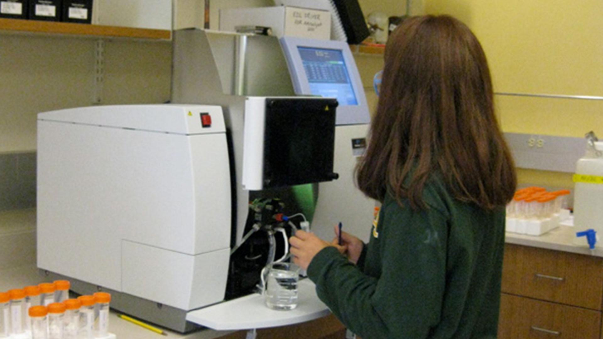 Student using an atomic absorption photometer in a lab.