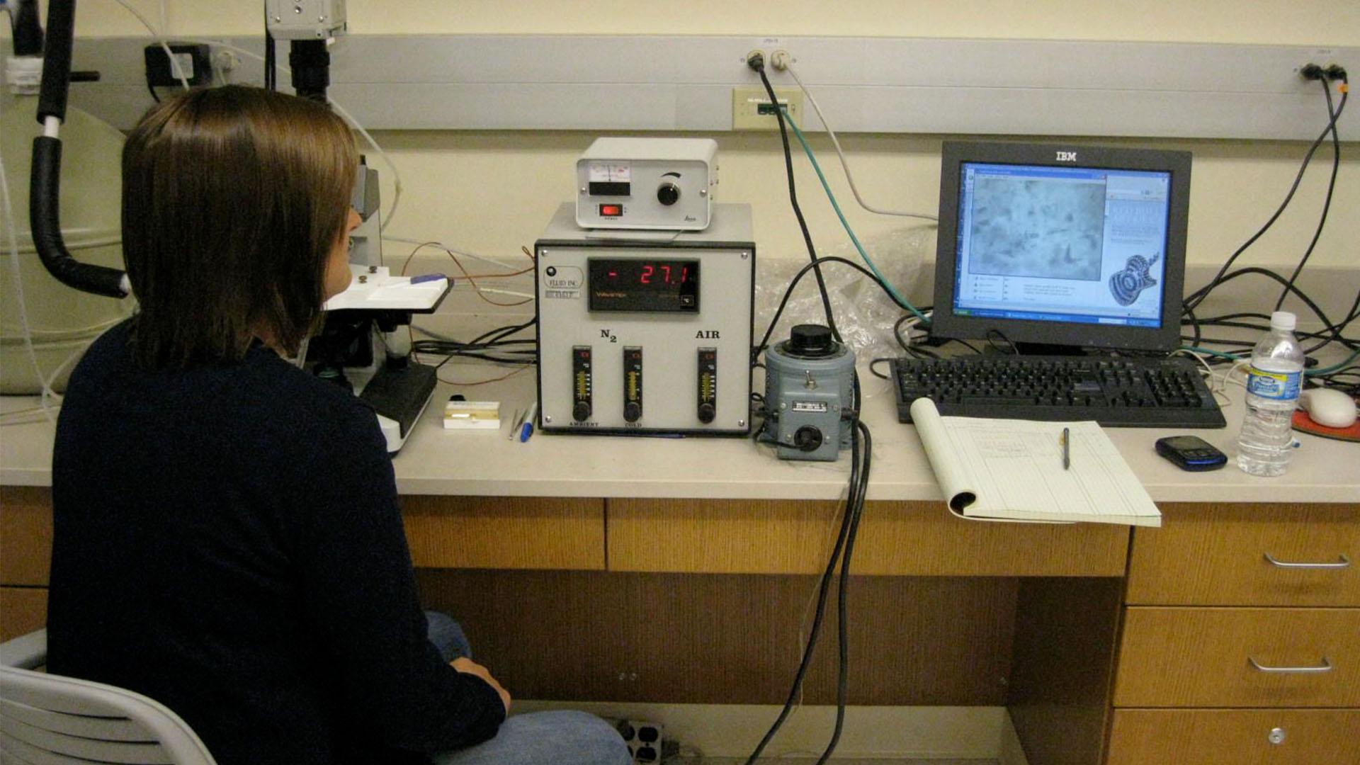 Student using fluid inclusion microthermic system in lab.
