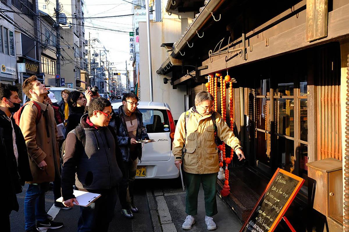 Students read tourism sign on Kyoto street.