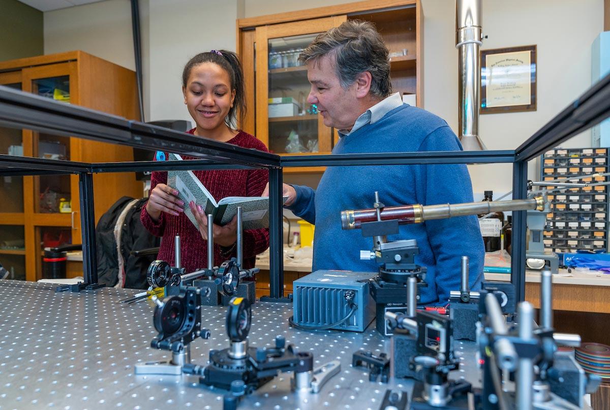 Enrique "Kiko" Galvez, Charles A. Dana Professor of Physics and Astronomy works with students in the laser lab in the Ho Science Center.