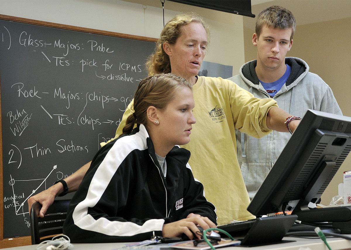 Karen Harpp points information out on a computer monitor to her student summer researchers.
