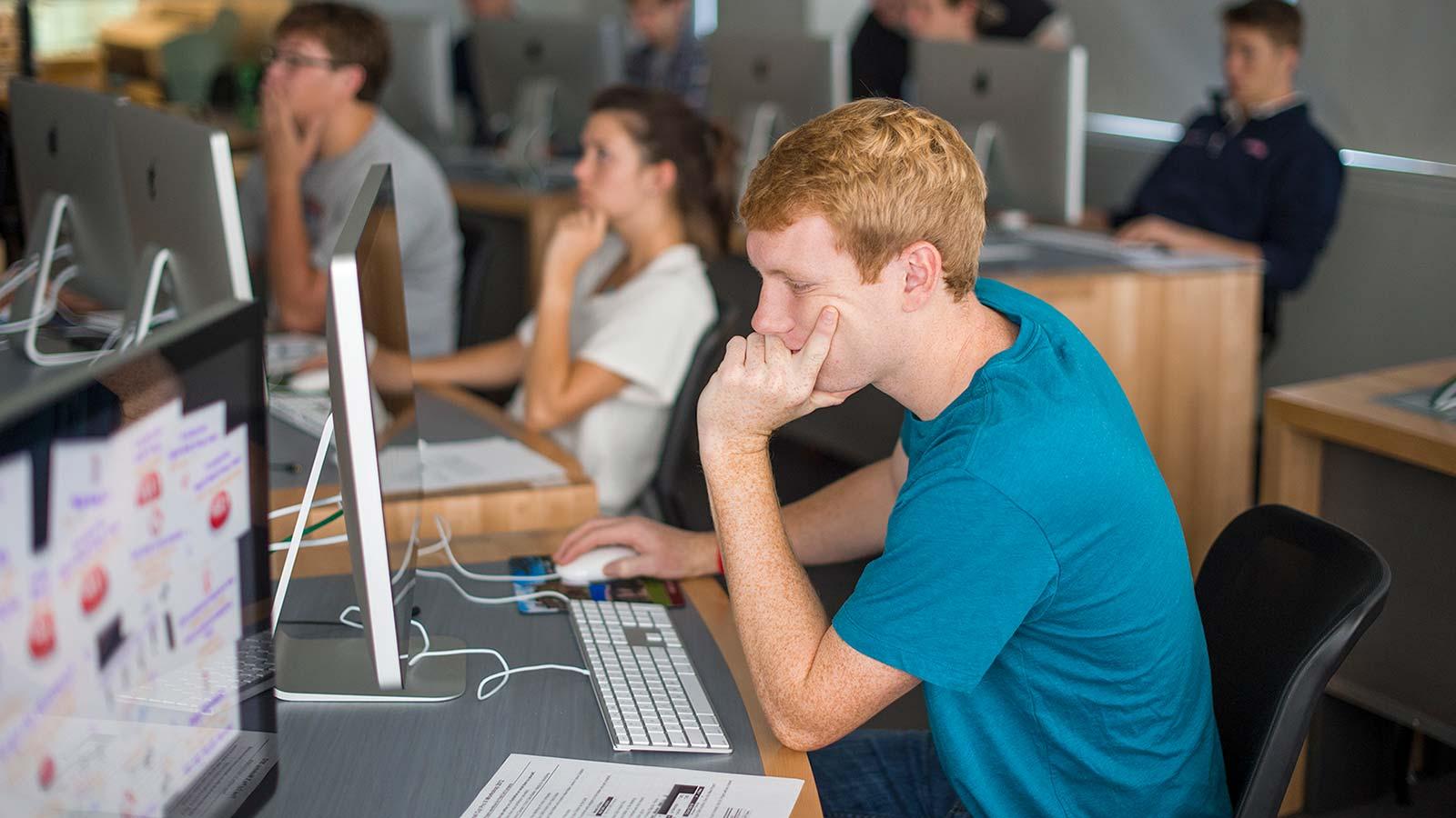 A student works at a Mac workstation in a computer lab