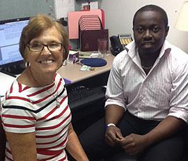 A student fellow and a community partner sitting together at a computer terminal.