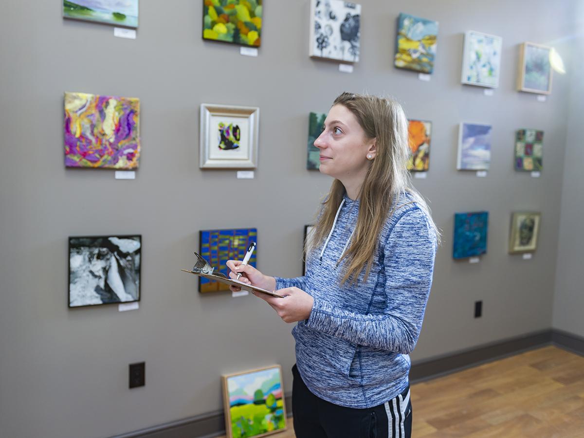 Student volunteer catalogs works in the Hamilton Center for the Arts.