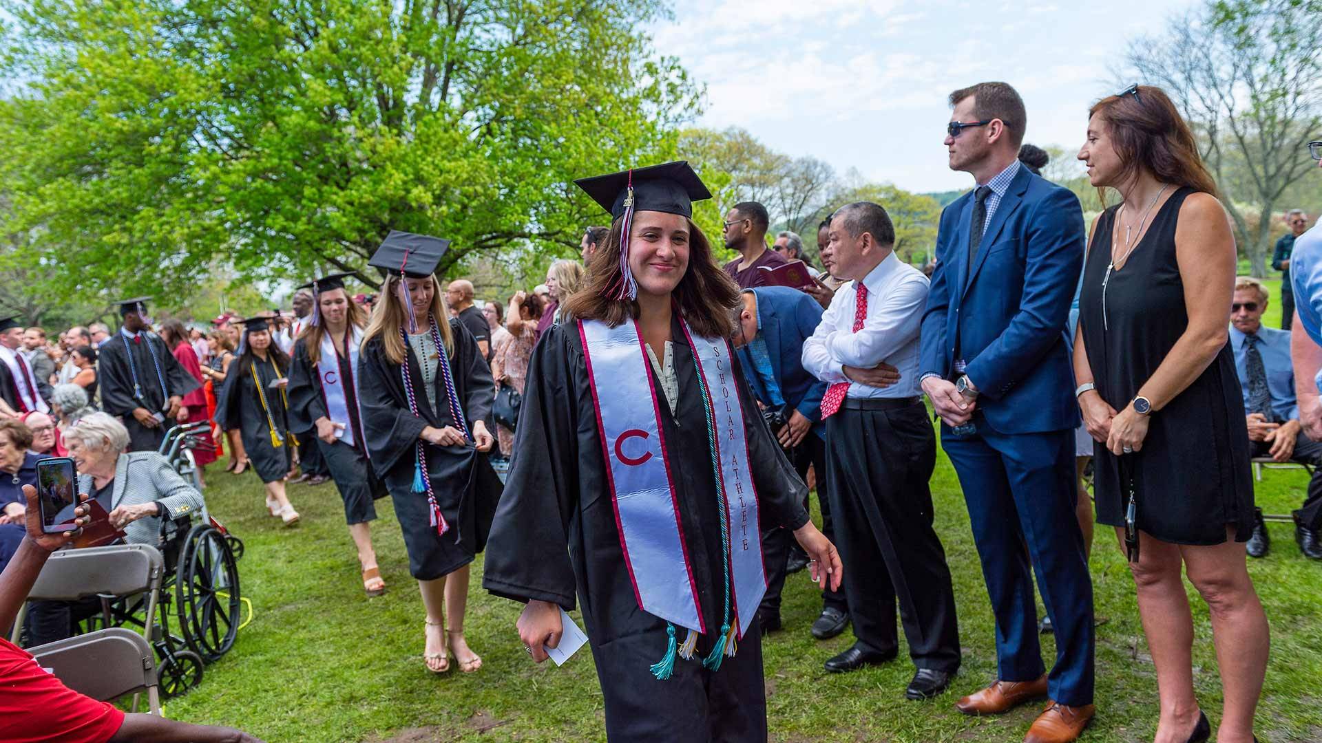 Students in caps and gowns walk for commencement