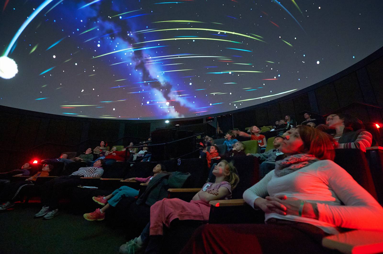 A class of gradschoolers looking up at a planetary display in the Vis Lab
