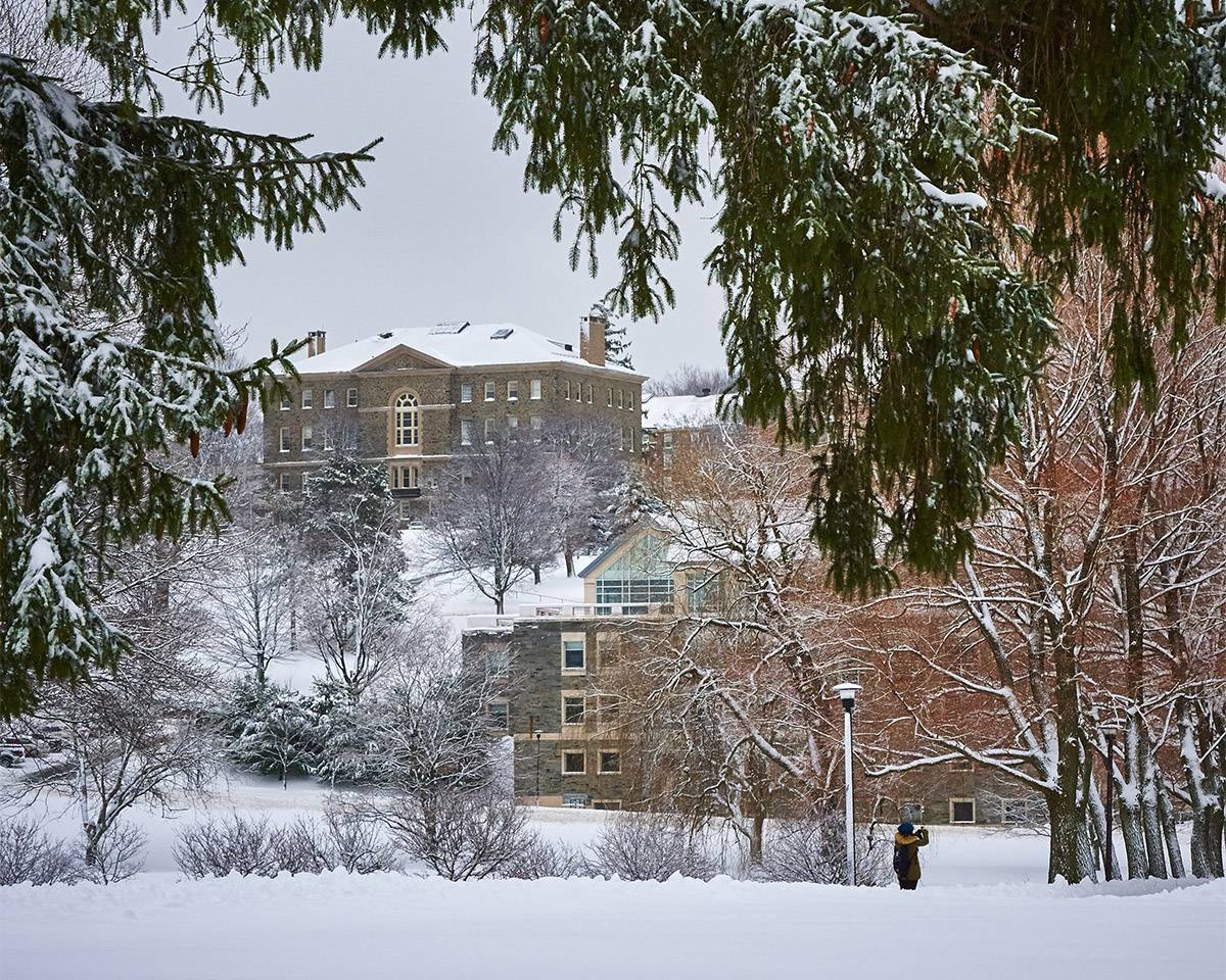 With campus as her backdrop, a student stops to take a photo of a wintry Willow Path