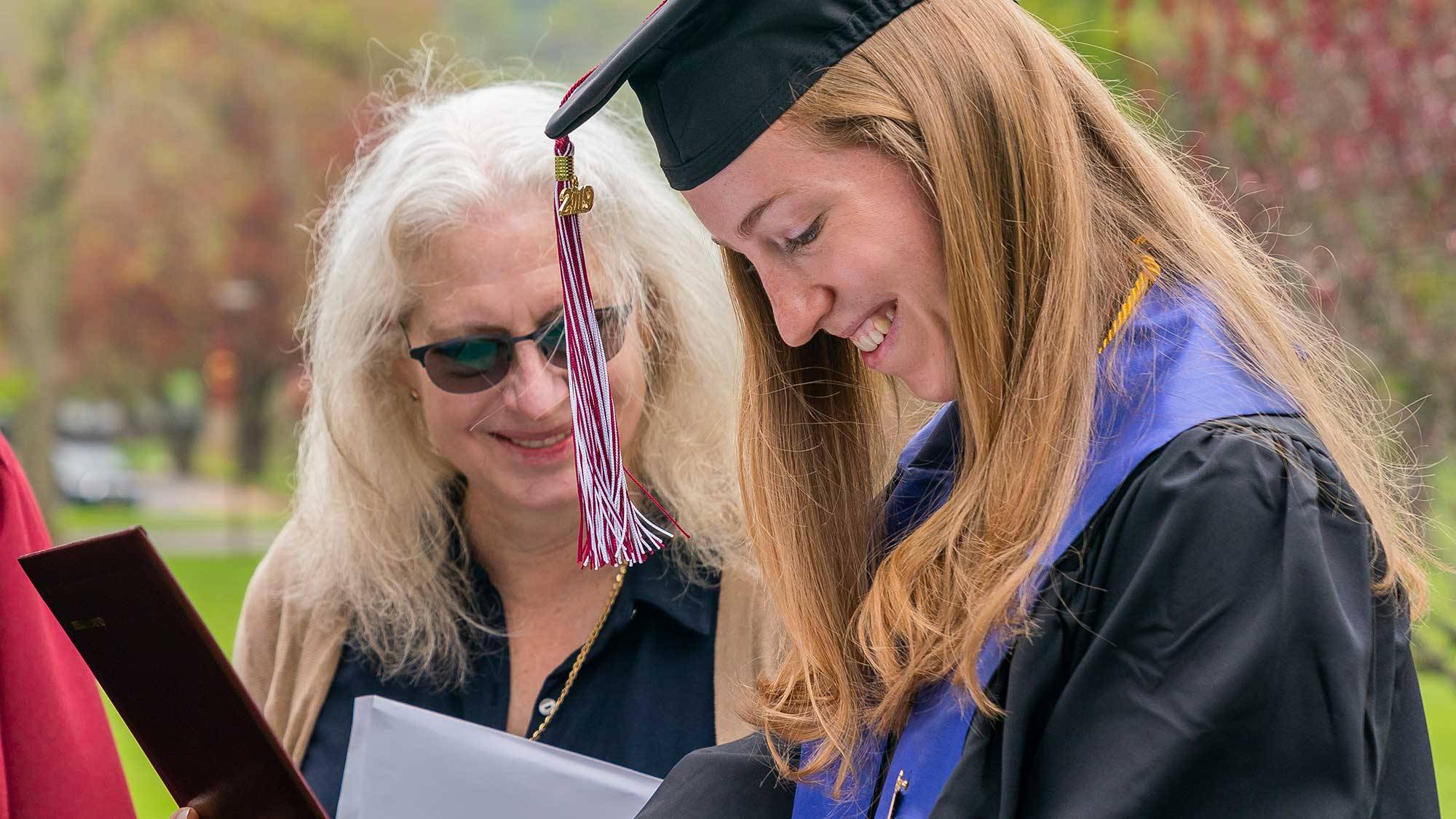 Caroline Hashagen looks at her diploma as her mother smiles in the background