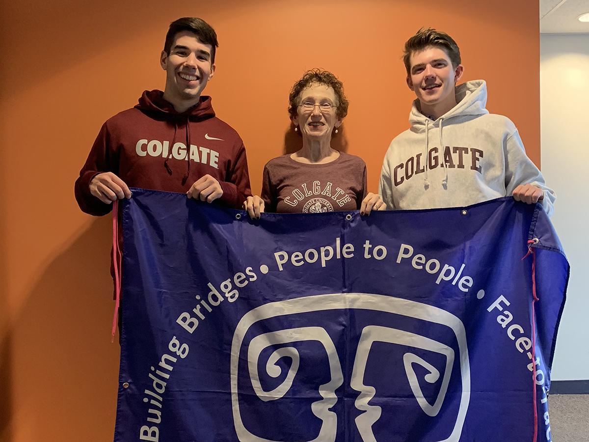 Students and an alumna holding a flag for a community center