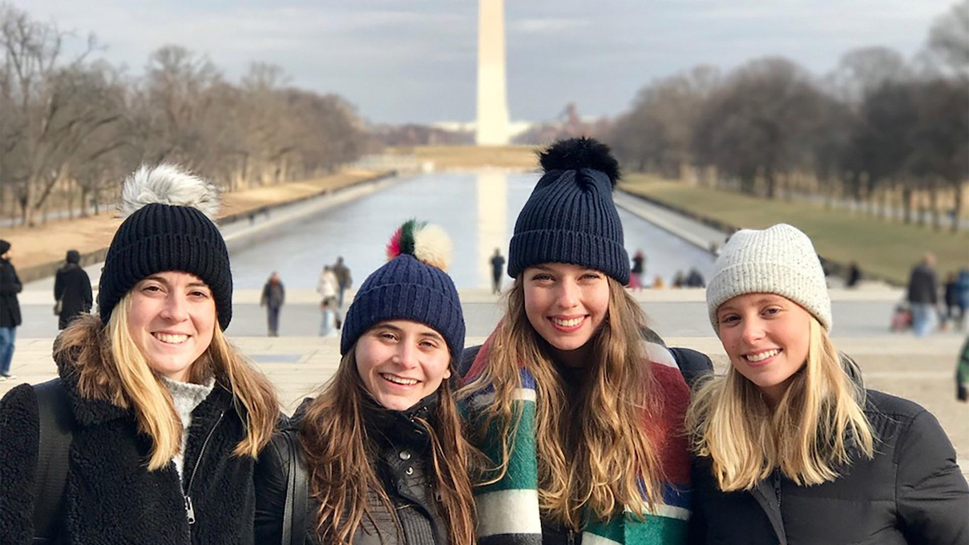 Four students with the Washington monument and reflecting pool in the background