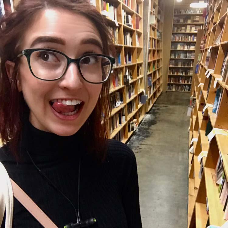 Erin Hoffman biting her tongue and smiling in the aisle of the Powell's bookstore