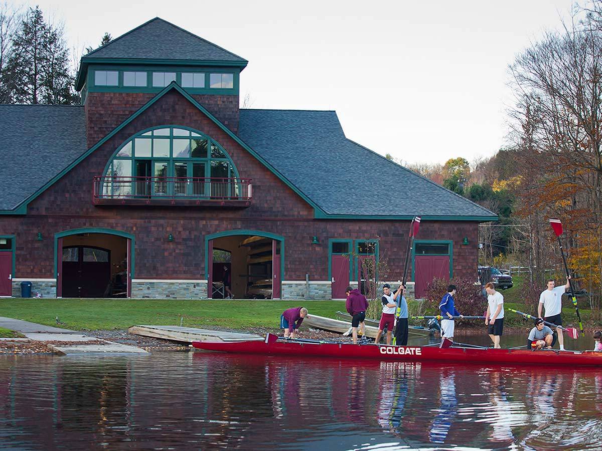 The men's rowing team prepares to remove their boat from the water on the dock at Glendening Boathouse