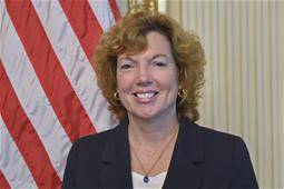headshot of Kathleen Doherty ’85 in front of the US flag
