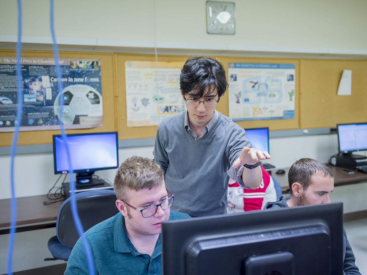 Students work at classroom computer workstations.