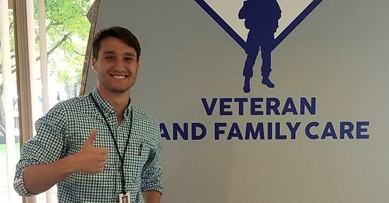 Peter Tappenden ’18 in front of a Veteran and Family Care sign