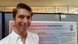 Man stands in front of his poster project and smiles.