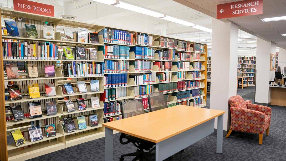 Stacks of books and a table in George R. Cooley Science Library