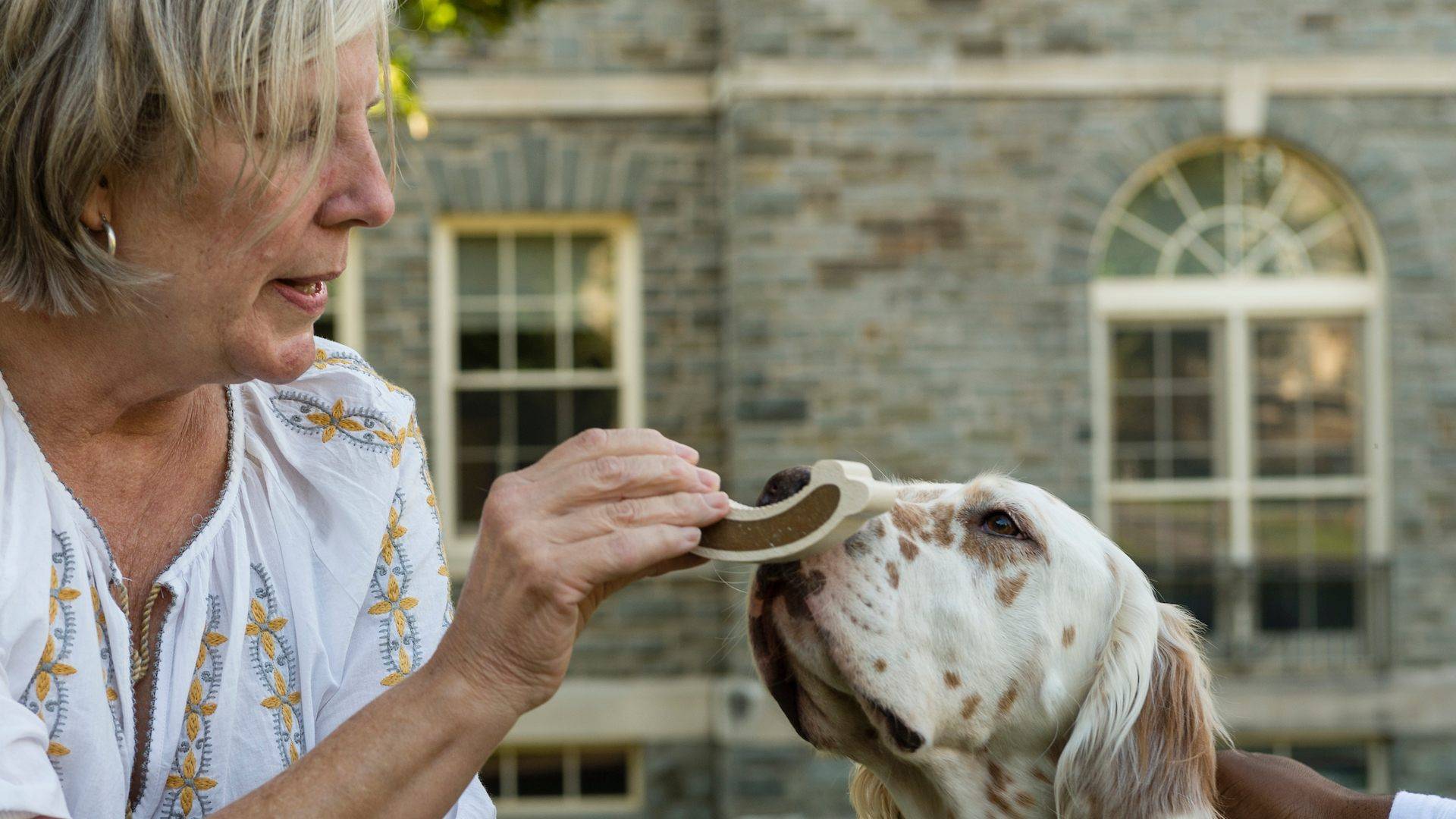 A staff member feeds her dog a treat on the Academic Quad