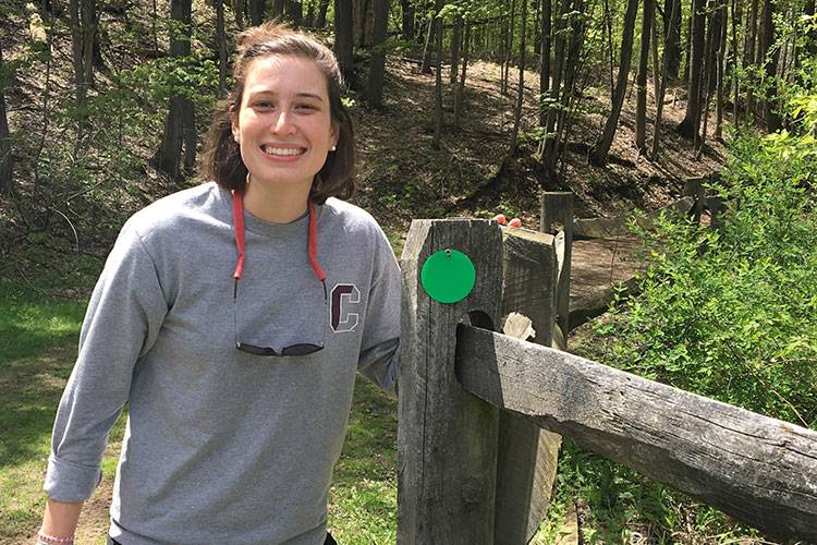 Student standing by fence at cross country trail