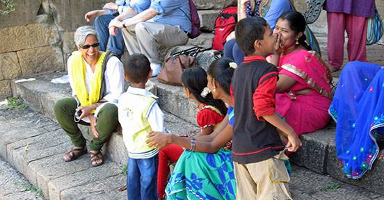 Padma Kaimal sitting on stone steps with a local family