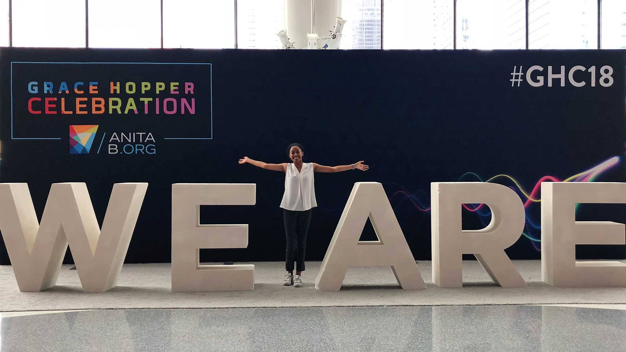 Brittney Chin ’21 stands in front of WE ARE sign at Grace Hopper celebration