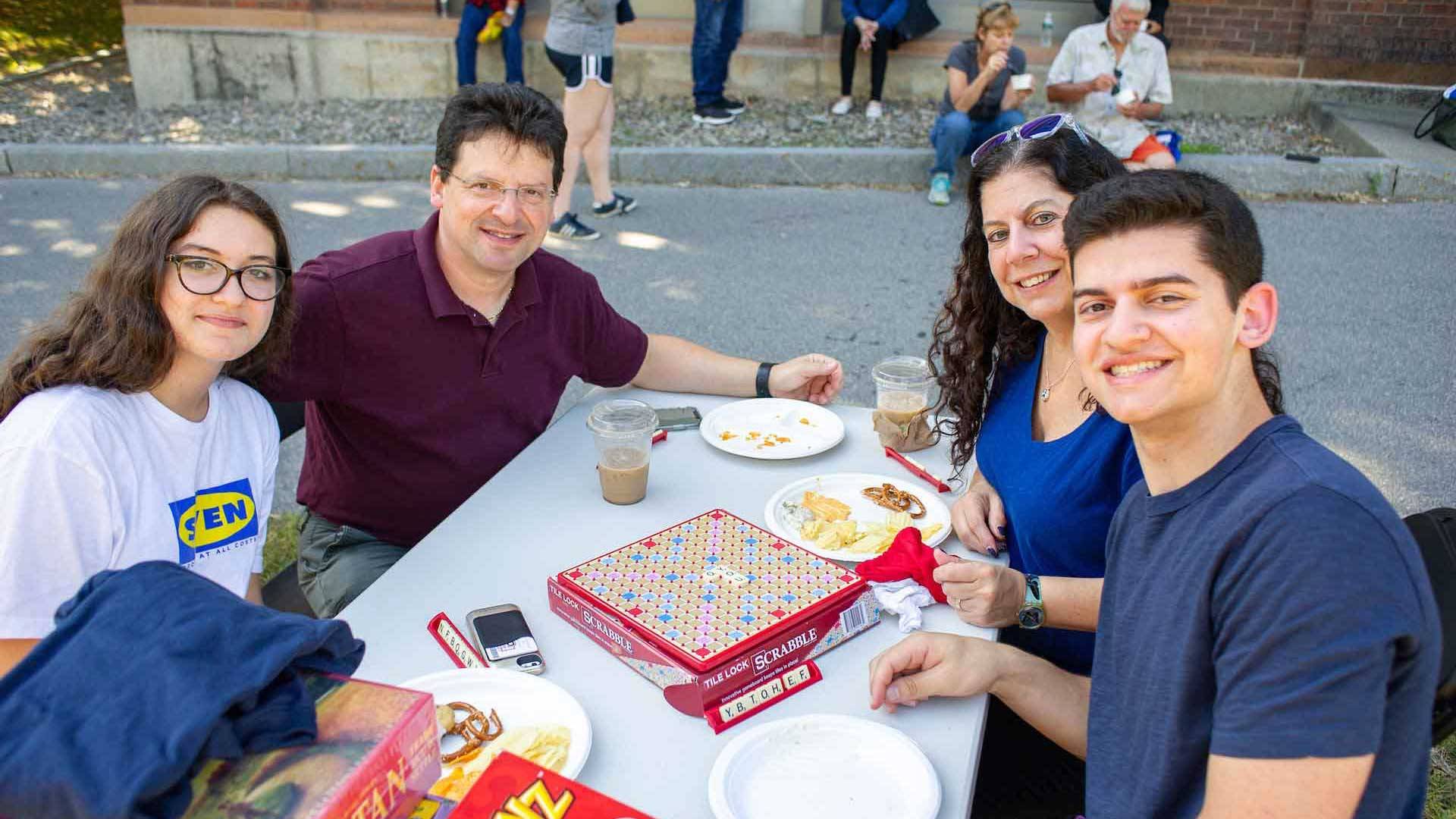 A family eats and plays games together at a picnic table