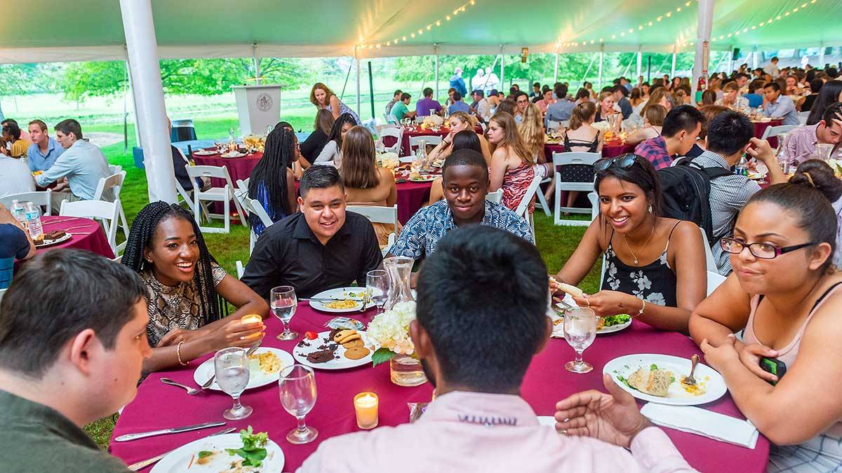 Students share a meal under a tent on Whitnall Field