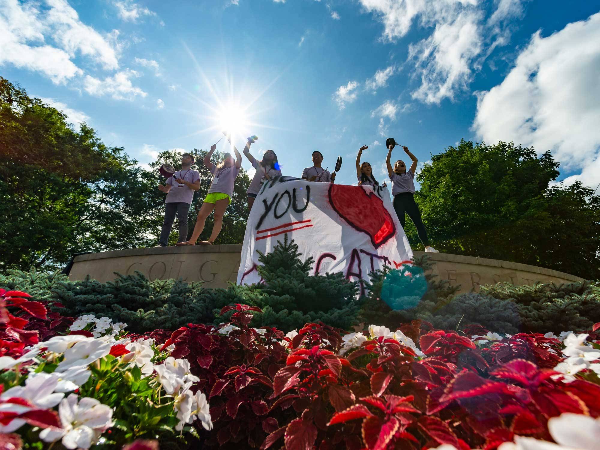 Students hold sign reading "honk if you love Colgate"