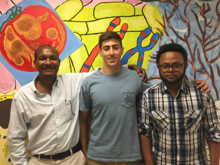 Professor and students standing in front of biology mural