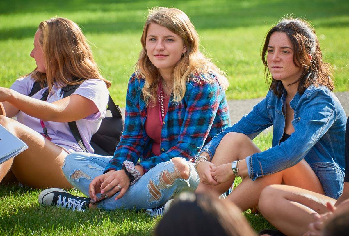 Students sitting in the grass during orientation