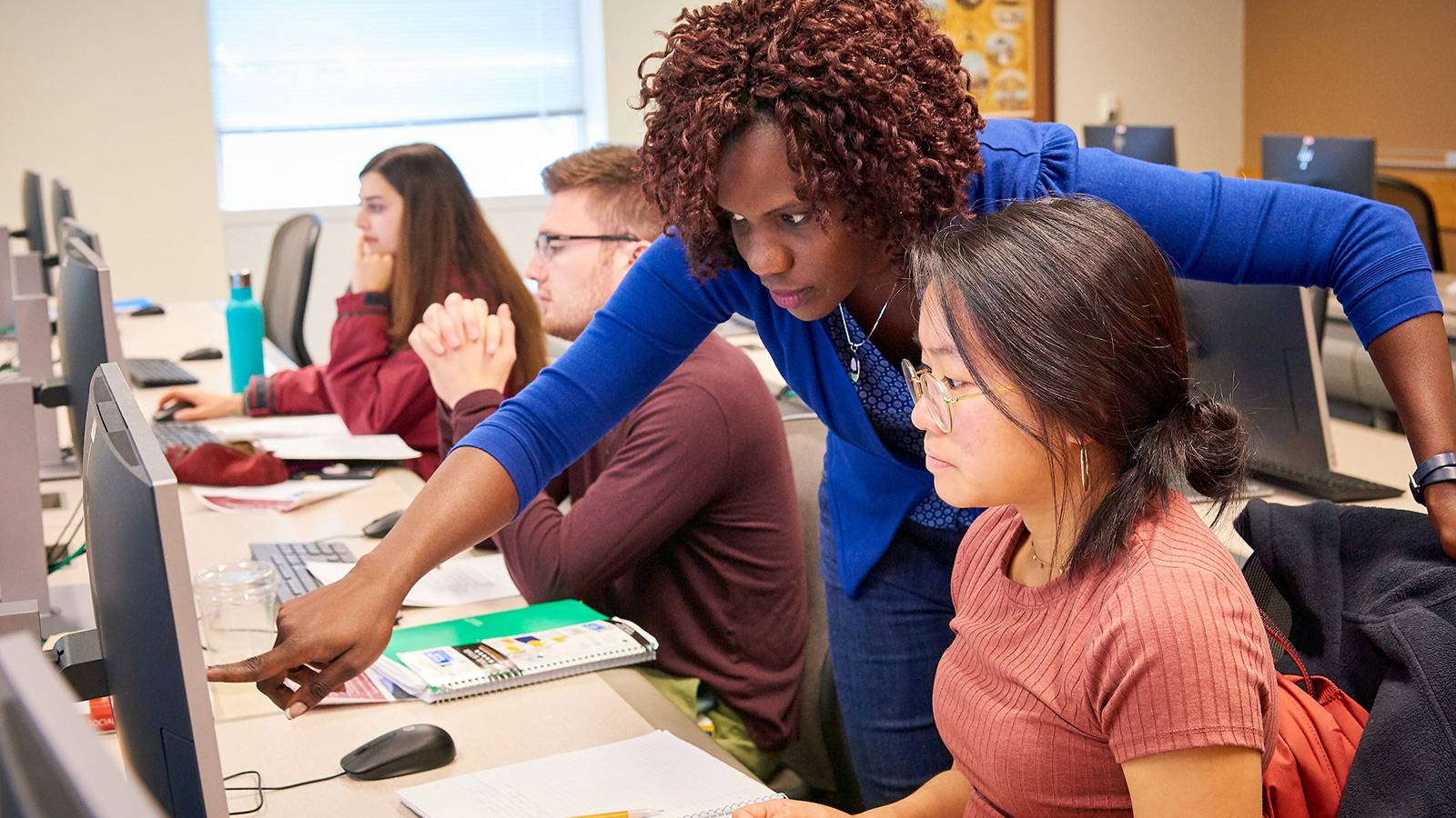 Professor instructing students at computer