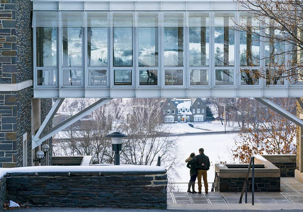 A couple embraces while standing at the top of the Persson Hall stairs