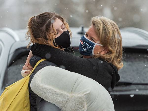 A student hugs a parent as she arrives on campus in the snow for the spring semester