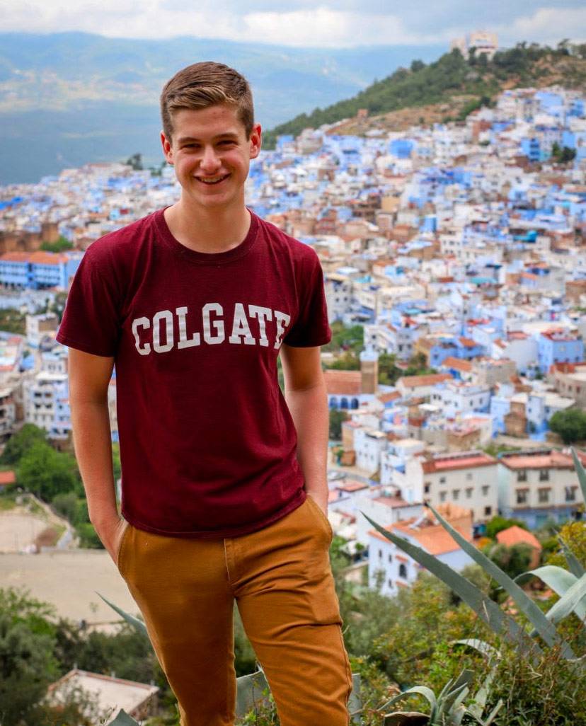 Cole standing in front of a village on a study abroad trip.